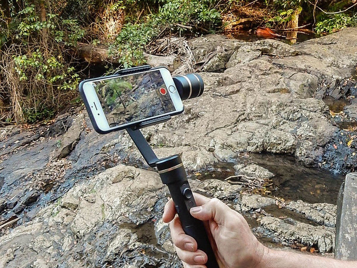 Handheld 3-axis gimbal holding a smartphone outdoors