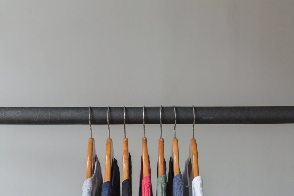 Wooden hangers on a rail with clothes hanging
